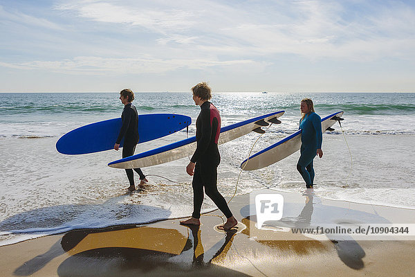 Portugal Lissabon Drei Personen mit Surfbrettern am Strand