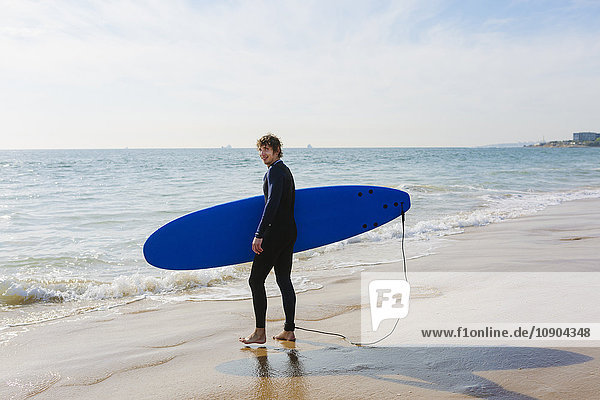 Portugal Lissabon Mann mit Surfbrett am Strand