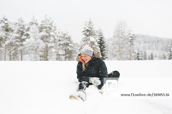 Finland  Jyvaskyla  Saakoski  Laughing young woman sitting in snow