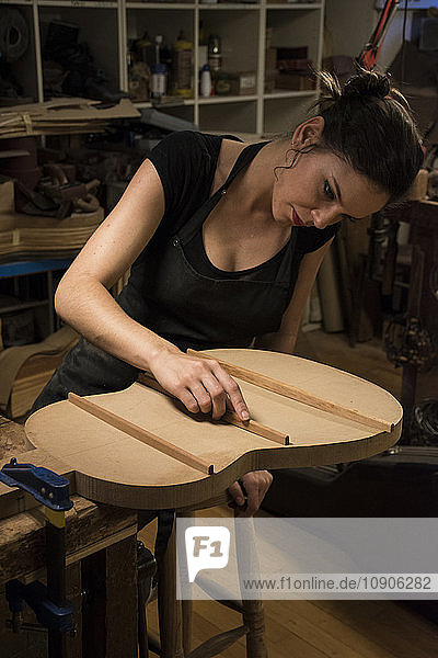 Luthier manufacturing a guitar in her workshop