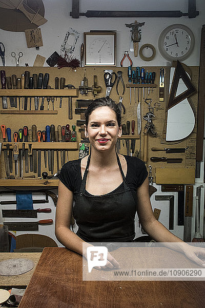 Portrait of smiling luthier in her workshop