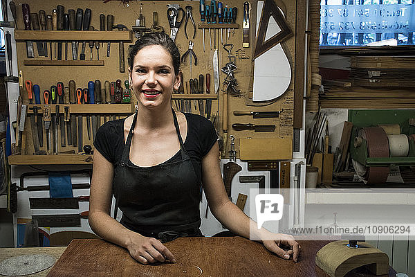 Portrait of smiling luthier in her workshop