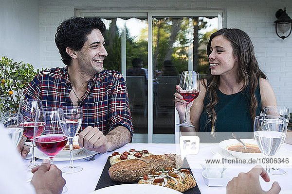Man and woman having fun and drinking lambrusco wine during a summer dinner