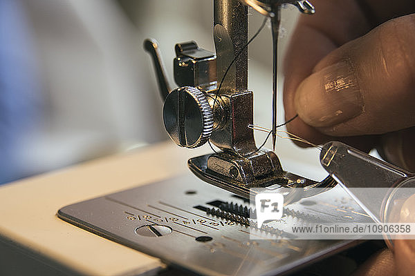 Woman adjusting thread in a sewing machine