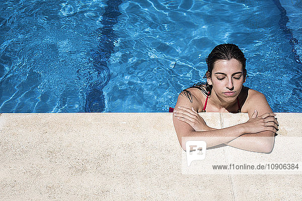 Portrait of a woman with closed eyes in a swimming pool relaxing at the edge