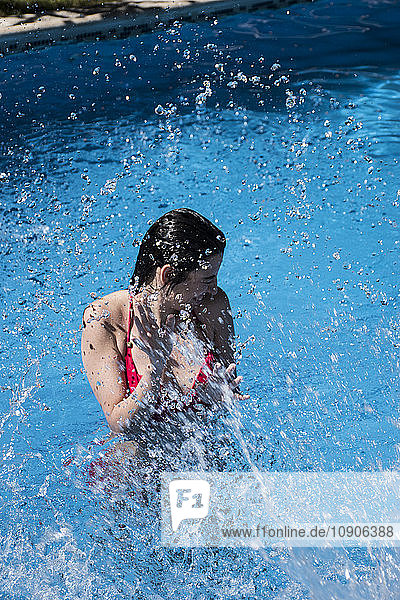 Woman standing in a pool being splashed with water