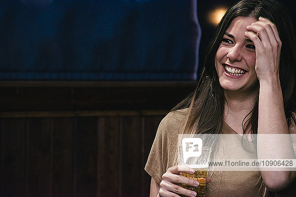Laughing woman with a glass of beer in a bar