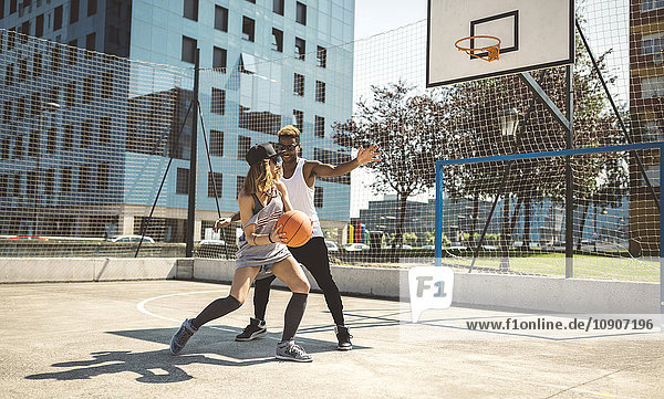 Junges Paar spielt Basketball auf dem Platz