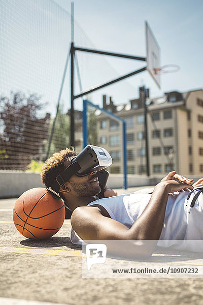 Junges Paar mit Virtual-Reality-Brille  ruhende Köpfe auf Basketball