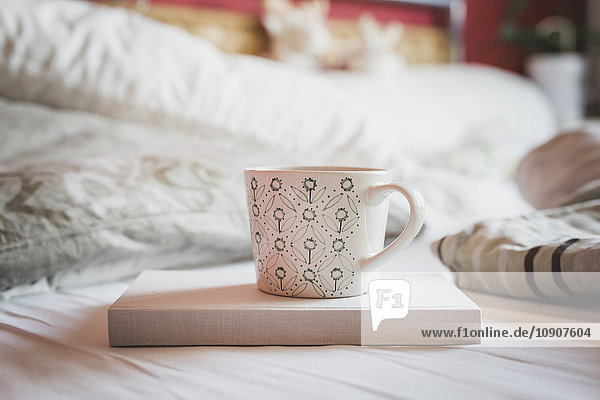 Buch und Tasse Kaffee auf einem Bett