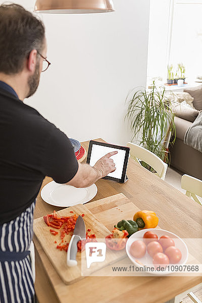 Man using digital tablet while preparing food in the kitchen