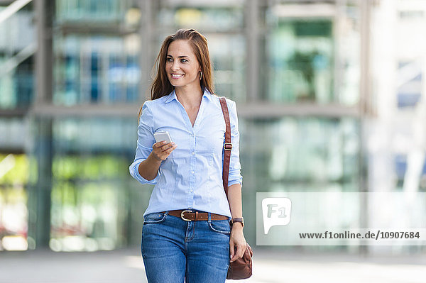 Lächelnde Frau mit Handy im Freien