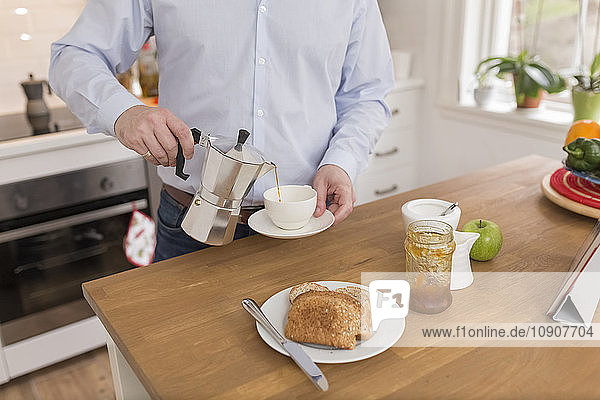 Man pouring espresso into cup in his kitchen  partial view