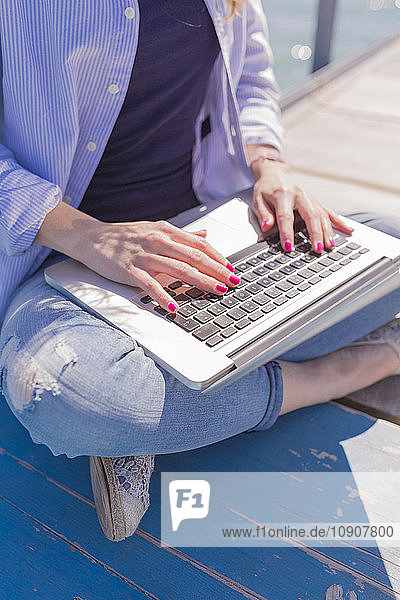 Woman using laptop on jetty