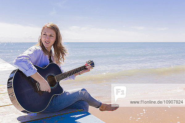 Woman playing guitar on jetty