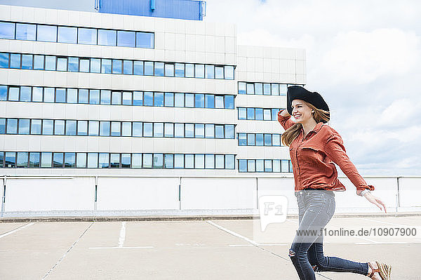 Woman with hat running on roof terrace