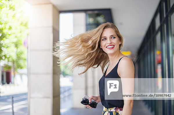 Portrait of smiling young woman tossing her hair