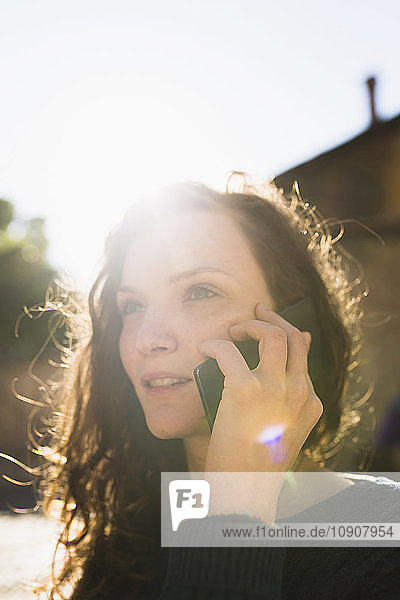 Portrait of smiling woman telephoning with smartphone