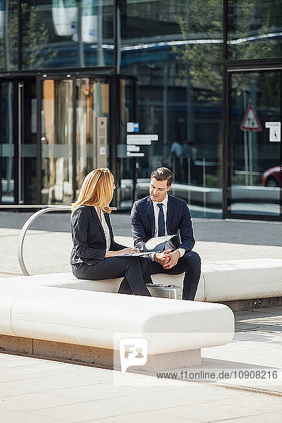 Businessman and businesswoman talking outside office building
