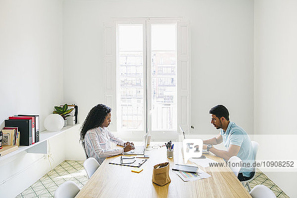 Young businessman and woman working together in office  using laptop