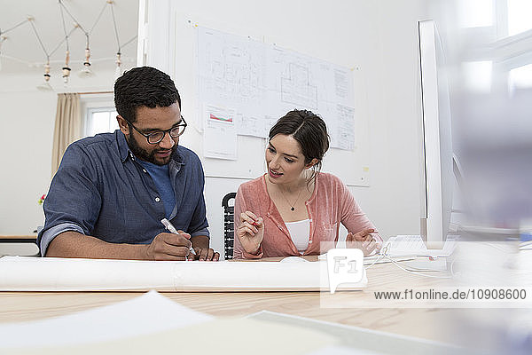 Man and woman discussing at desk in office
