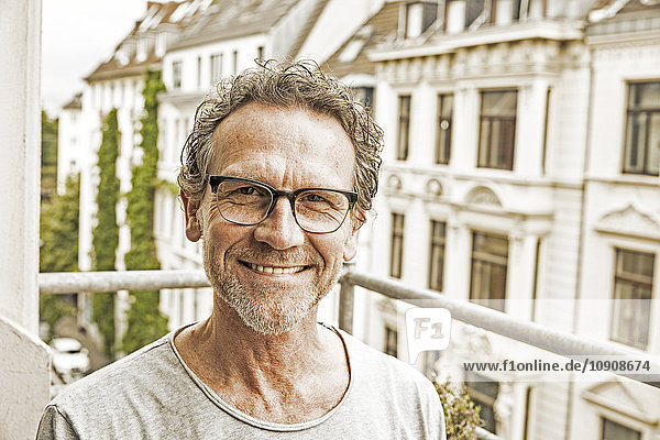 Porträt eines glücklichen Mannes mit Brille auf dem Balkon