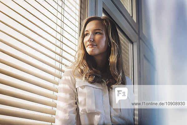 Young woman looking through window