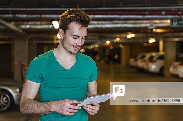 Portrait of smiling young man with digital tablet in underground car park