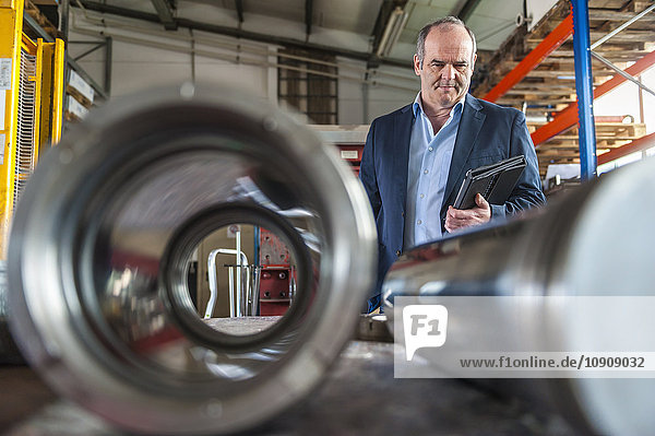 Workshop  senior man with digital tablet looking on hydraulic cylinder