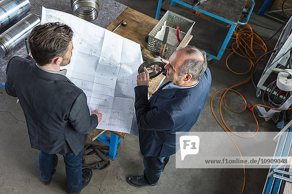 Two engineers with construction plan talking  hydraulic cylinder