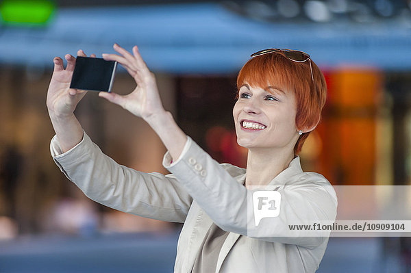 Lächelnde junge Frau  die einen Selfie nimmt.