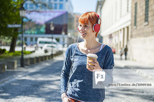 Lächelnde junge Frau mit Kaffee zum Musikhören