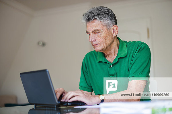 Senior man sitting at desk using laptop