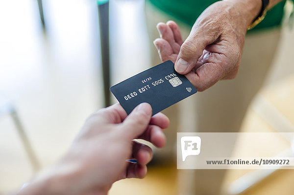 Nahaufnahme von zwei Händen mit Kreditkarte