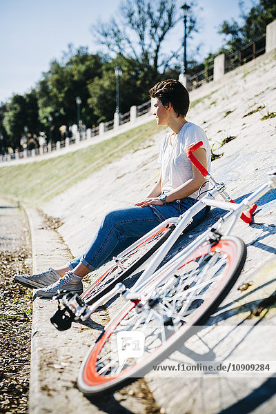 Junge Frau mit Fahrrad auf geneigter Wand sitzend