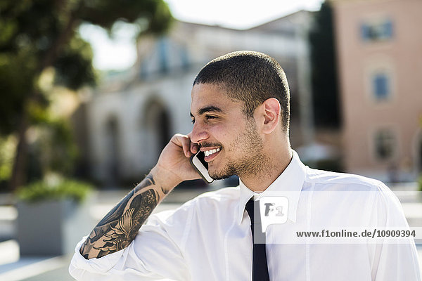 Smiling young businessman telephoning with smartphone