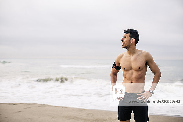 Sportive young man standing on the beach