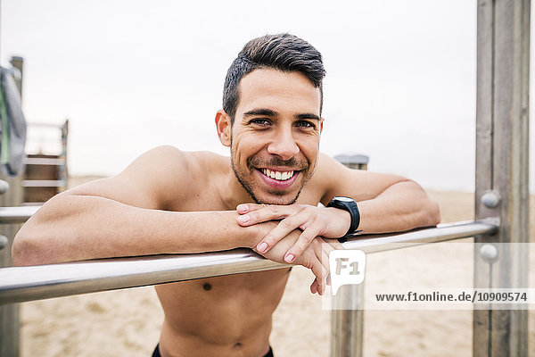 Porträt eines lächelnden Sportlers an Bars am Strand