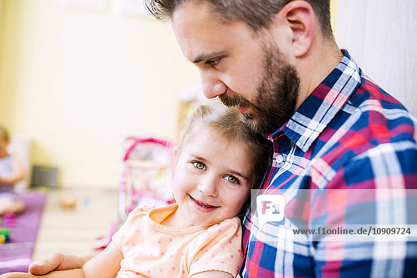 Little girl sitting on father's lap  smiling