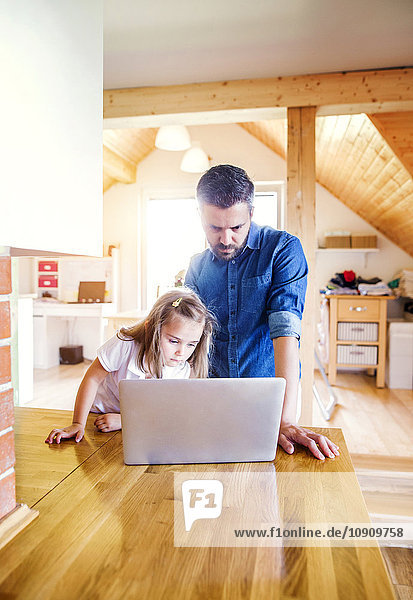 Vater und Tochter mit dem Laptop zu Hause