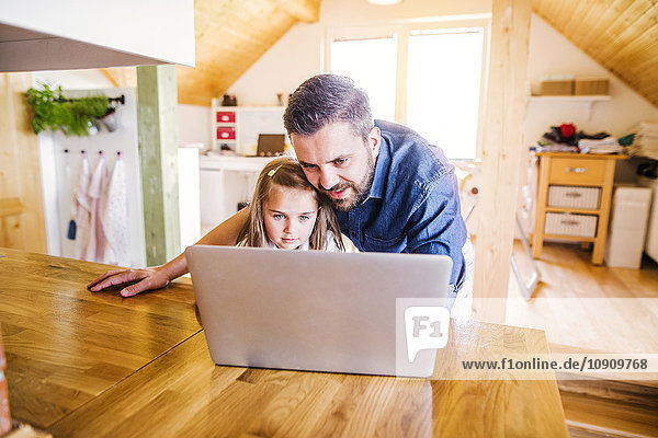 Vater und Tochter mit dem Laptop zu Hause