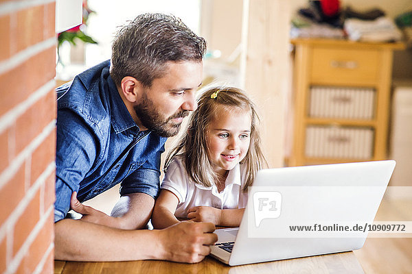 Vater und Tochter mit dem Laptop zu Hause