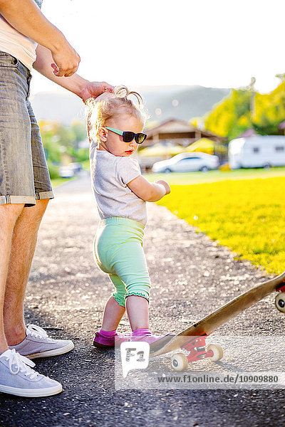 Porträt des Kleinkindes mit Sonnenbrille  das Skateboard tritt