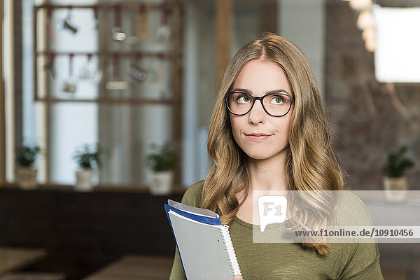 Portrait of sceptical blond woman with notebook in a coffee shop