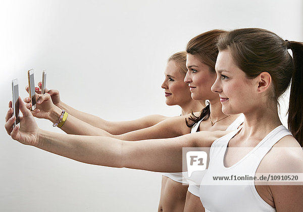 Reihe von drei jungen Frauen  die Selfie mit ihren Smartphones nehmen
