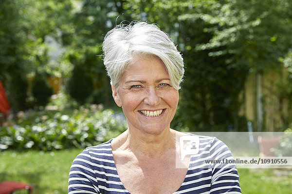 Porträt einer lächelnden Frau im Garten