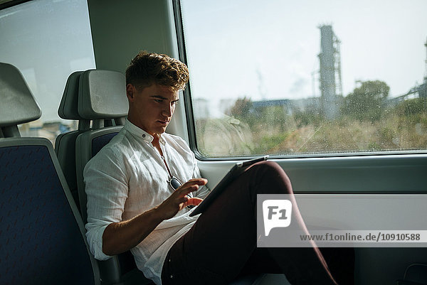 Young man using a tablet on a train