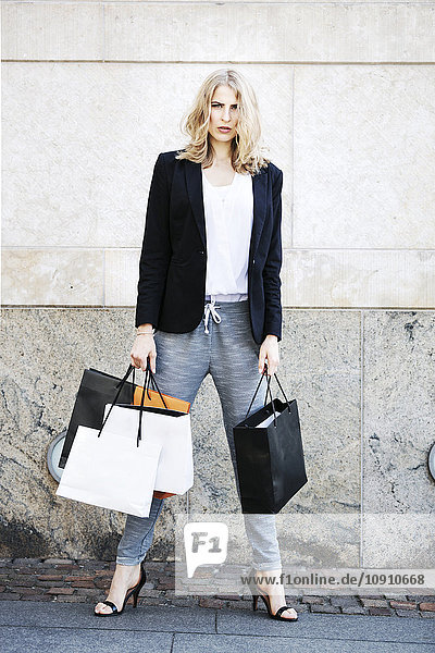 Porträt einer ernsthaft aussehenden Frau mit vielen Einkaufstaschen