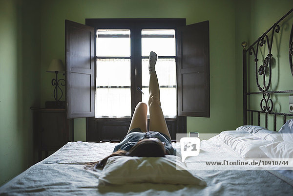 Entspannte Frau im Bett liegend mit Smartphone