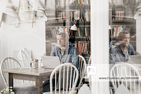 Reifer Mann sitzt im Café mit Laptop